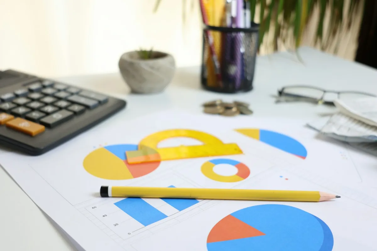 A desk with printed charts, a calculator, and a pencil