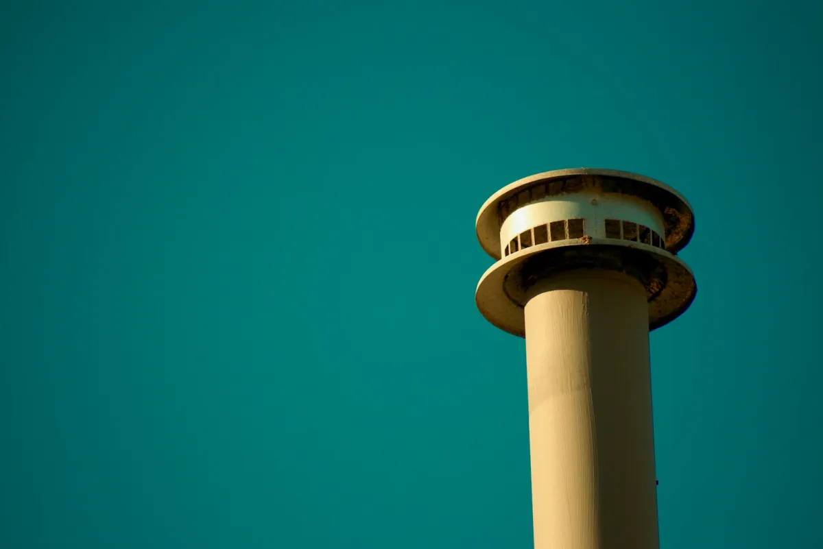 An air traffic control tower against a teal sky