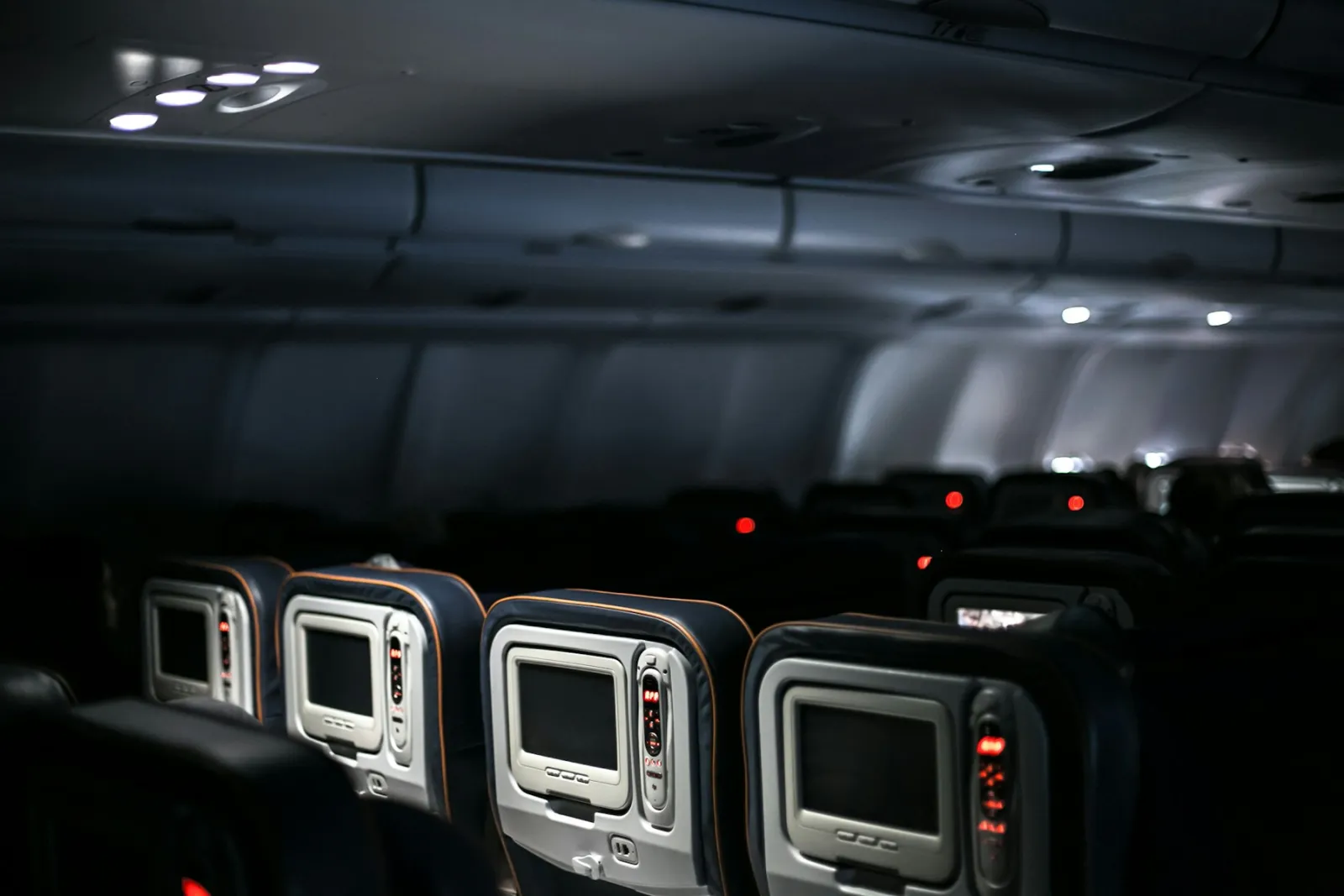 Rows of airplane seatback screens in a dimly lit cabin